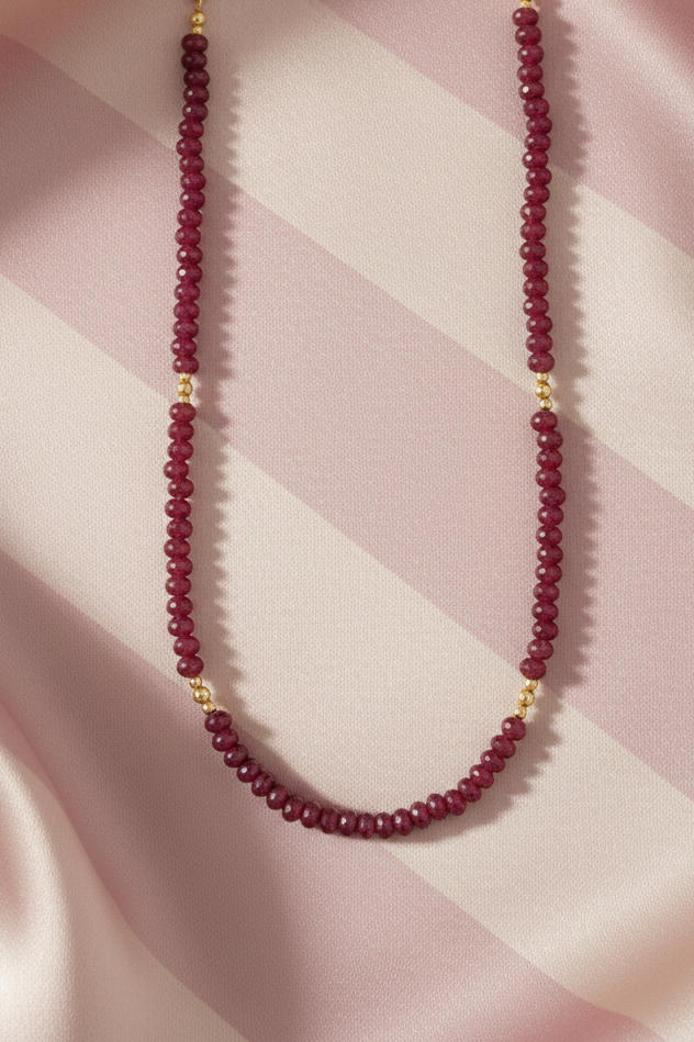 Collier rubis flat lay - fond rose poudre rayures crème