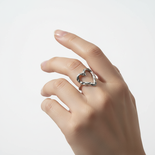 Bague cœur argenté sur doigt angle différent fond blanc