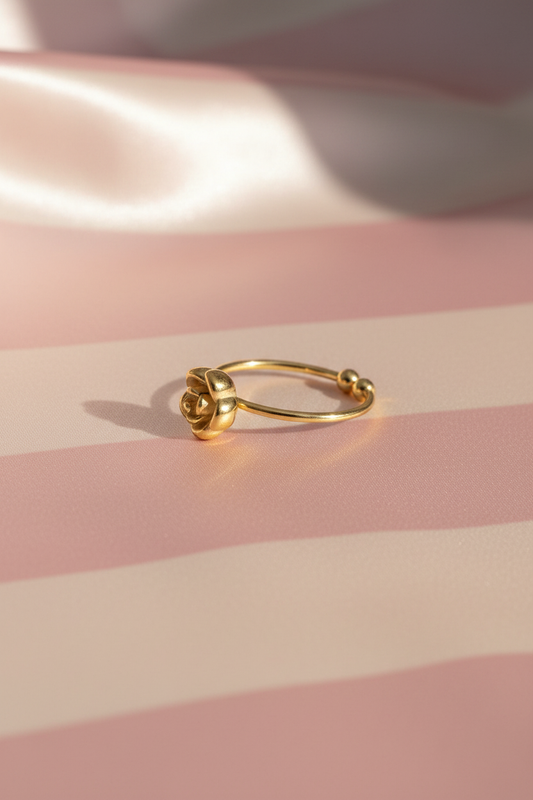 Bague fleur dorée billes vue en angle sur rayures rose poudre et crème satiné