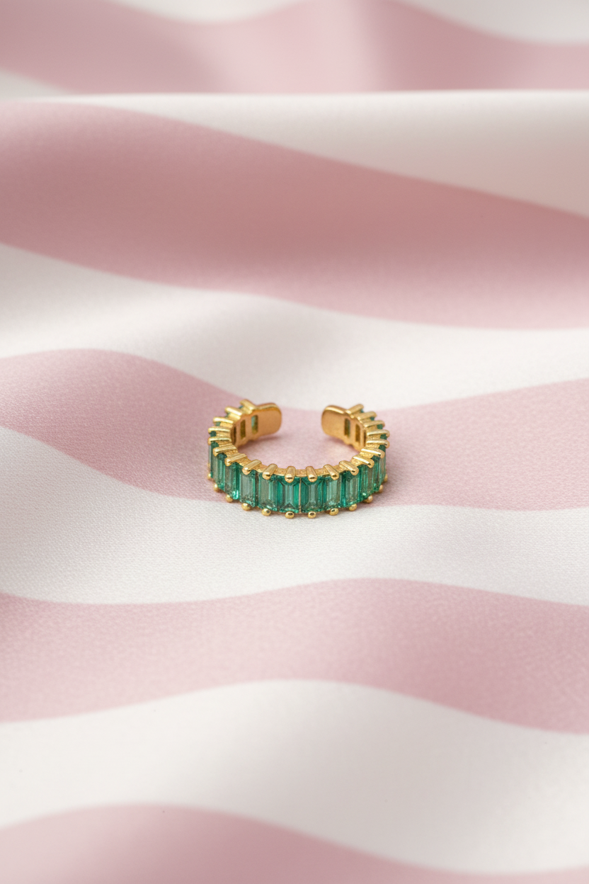 Bague jonc émeraude dorée vue de face sur rayures rose poudre et crème satiné