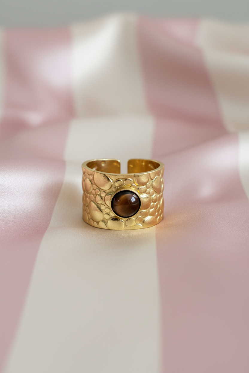Bague manchette dorée œil de tigre vue de face sur rayures rose poudre et crème satiné