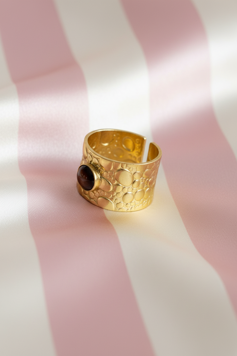Bague manchette dorée œil de tigre vue en angle sur rayures rose poudre et crème satiné