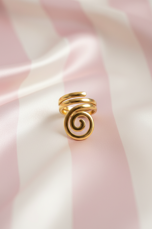 Bague spirale dorée vue de face sur rayures rose poudre et crème satiné