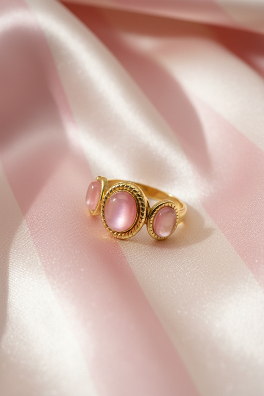 Bague trio pierres roses dorée vue en angle sur rayures rose poudre et crème satiné