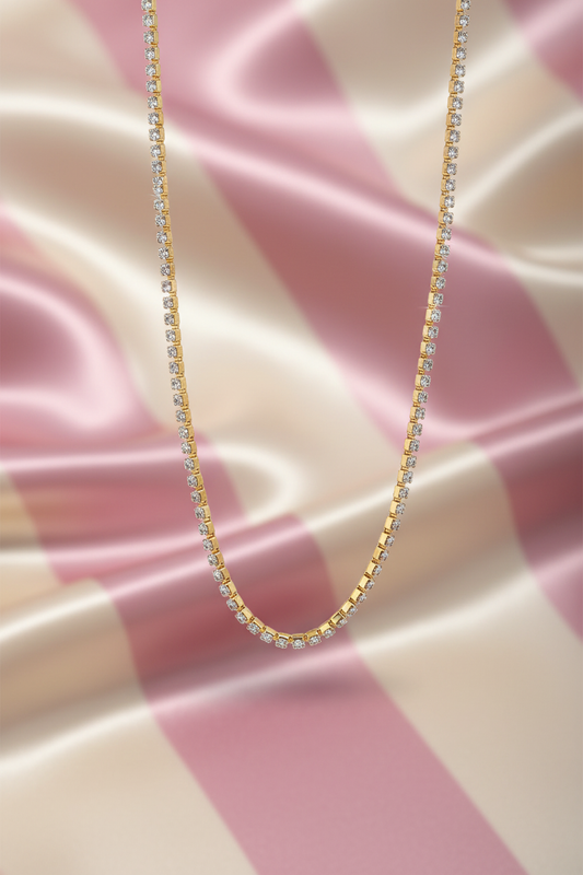Collier tennis or - flat lay - fond rayé rose crème